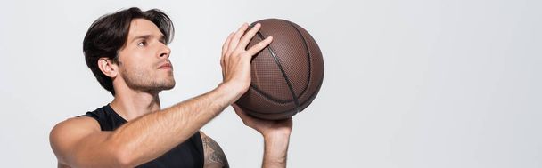 Bruneta sportovec v košili bez rukávů drží basketbal izolované na šedé, prapor  - Fotografie, Obrázek