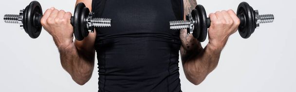 Cropped view of sportsman working out with dumbbells isolated on grey, banner  - Foto, immagini