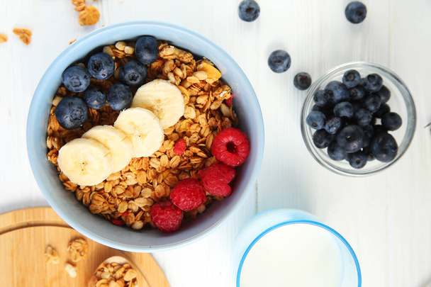 Granola with fruit on a white background. Granola with raspberries, blueberries and banana. - Photo, Image