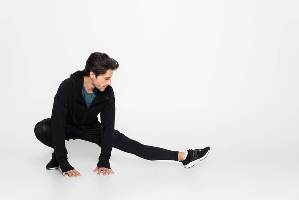 Brunette sportsman stretching on grey background  - Fotó, kép