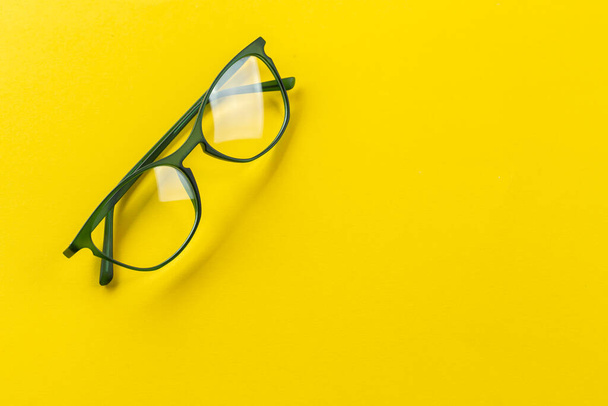 Stylish eyeglasses over yellow background. Optical store, glasses selection, eye test, vision examination at optician, fashion accessories concept. Space for text. - 写真・画像