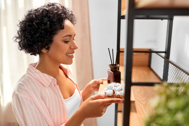 woman with aroma reed diffuser and cotton at home - Foto, afbeelding