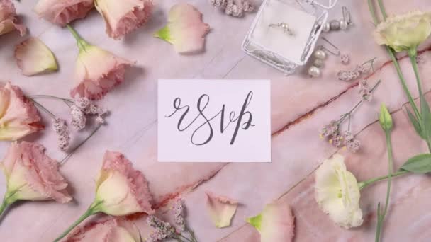 Carte RSVP sur une table en marbre près de fleurs roses vue du dessus zoom avant  - Séquence, vidéo