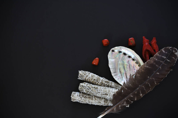 Ein Bild von oben mit weißen Salbeischmierstöcken und Seeohr-Muschel auf schwarzem Hintergrund.  - Foto, Bild