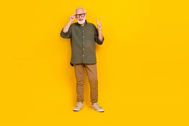 Full size portrait of cheerful satisfied aged person touch glasses show v-sign isolated on yellow color background - Fotografie, Obrázek