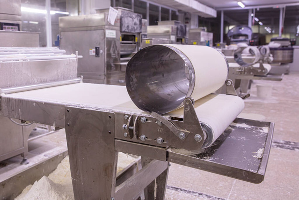 Panadero haciendo masa para la pastelería en lámina de masa. Máquina de laminación de masa para la producción de pasteles, pan y baklava. - Foto, Imagen