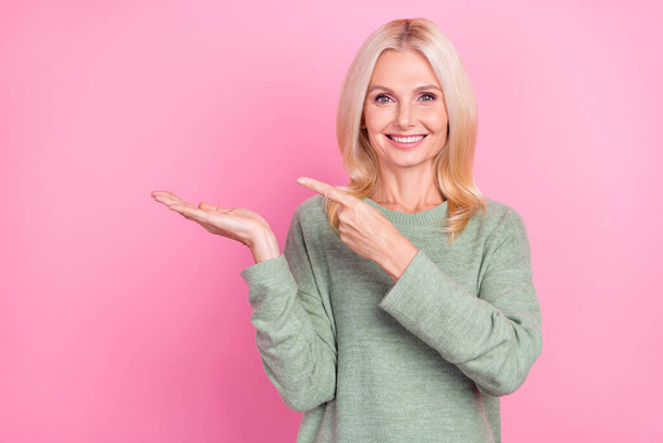 Photo of charming cute lady pensioner dressed green pullover holding arm empty space isolated pink color background - Φωτογραφία, εικόνα