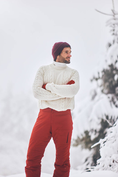 Man in ski suit and sweater in snowy forest during winter vacations outdoors - Fotoğraf, Görsel
