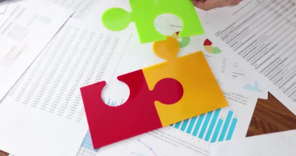 Équipe d'affaires collecter des pièces de puzzle en plastique multicolore sur le bureau - Séquence, vidéo