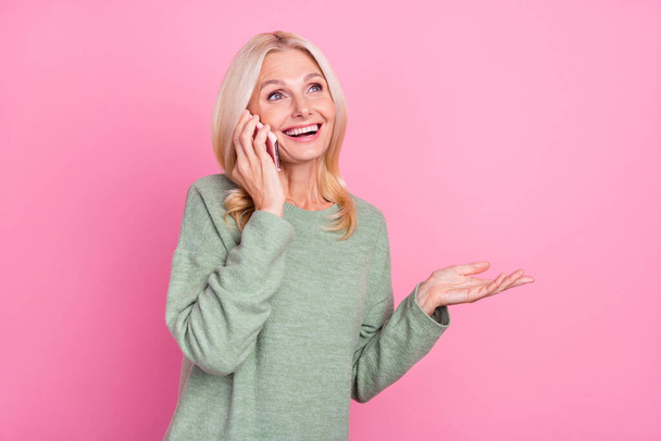 Photo of cute aged blond lady talk telephone wear grey jumper isolated over pink color background - Fotografie, Obrázek