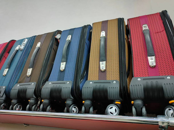 разноцветные тканевые чемоданы на колёсах на полке супермаркета - Фото, изображение