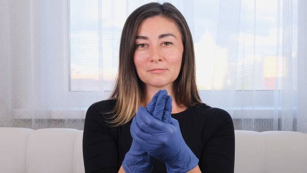 Mavi koruyucu eldivenli bir kadın virüs salgınını önlemek için el yıkama jeli dezenfektanı kullanıyor.. - Fotoğraf, Görsel
