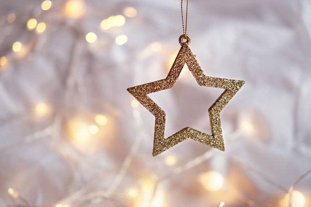 Estrella dorada brillante sobre un fondo suave con bokeh amarillo de la guirnalda. Composición de Navidad ligera, tema navideño - Foto, Imagen