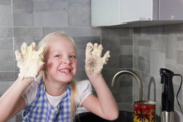 A little girl got her hands dirty with the dough while cooking. Happy family weekend concept. - Foto, afbeelding