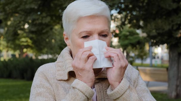 Senhora alérgica de meia-idade se sente mal ter sintoma de gripe, doente velha mulher madura segurar espirros de tecido tem febre pegou frio soprando nariz corrente no lenço, doente. Conceito de alergia, vista de perto - Foto, Imagem