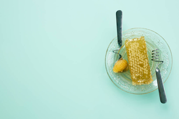 Healthy sugar, a golden honeycomb of natural honey on a plate dripping with sweetness, green and pastel background, Flat lay, Place for text - Photo, image