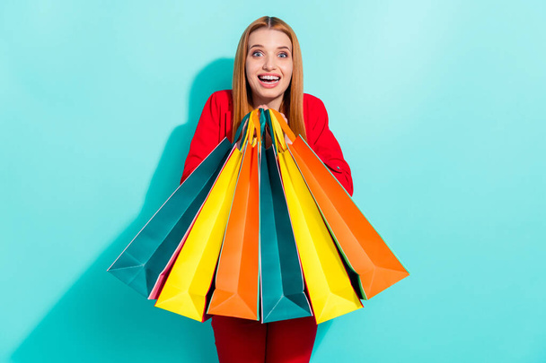 Photo of pretty impressed orange hair lady wear red blazer holding colorful shopping bags isolated cyan color background - Fotó, kép