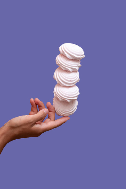 marshmallow plovoucí ve vzduchu pod rukou proti fialovému pozadí  - Fotografie, Obrázek