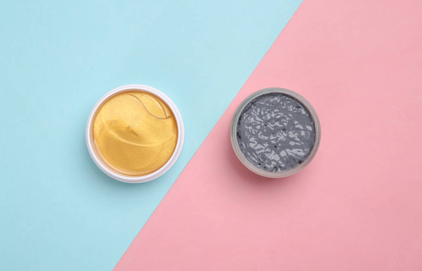 Black clay and golden patches on pink blue background. Beauty products, cosmetics. Top view - Foto, imagen