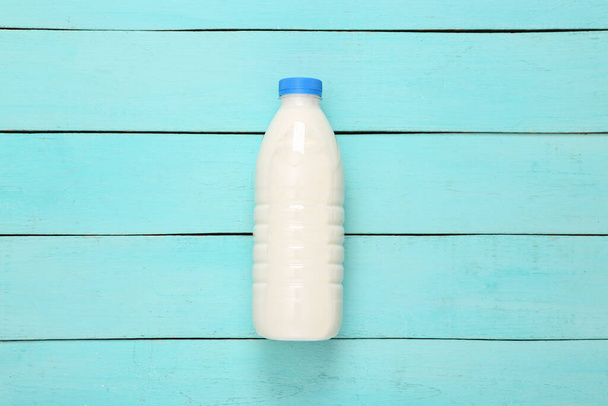 Milchflasche auf blauem Holztisch. Ansicht von oben - Foto, Bild