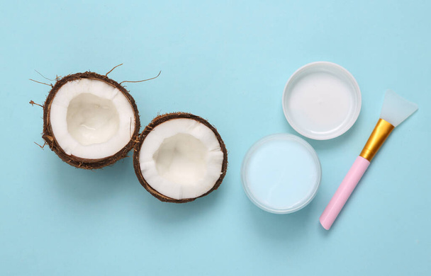 Potje gezichtscrème met kokosnoot op een blauwe achtergrond. Bovenaanzicht - Foto, afbeelding