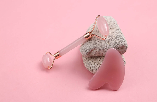 Rodillo de masaje facial con piedra natural sobre fondo rosa - Foto, Imagen