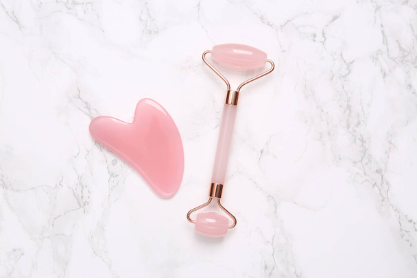Face roller and gua sha stone massager on marble background - Foto, immagini