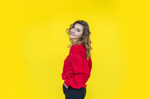 mujer de moda en clásico suéter de punto rojo posando y sonriendo sobre fondo amarillo. estilo de vida - Foto, Imagen