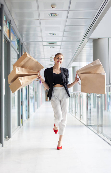 Belle femme blanche gaie avec des sacs à provisions dans le centre commercial. - Photo, image