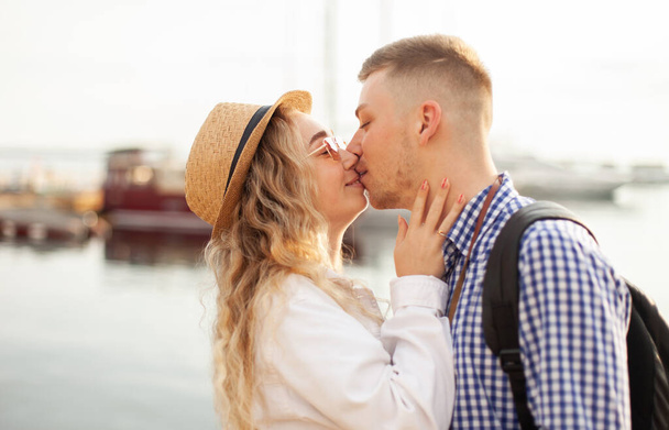 Young loving couple of tourists kiss on the background of the yacht club. Love, travel concept - Photo, Image