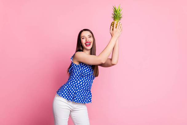 Portrait of attractive cheerful girl holding ananas dancing having fun isolated over pink pastel color background - Foto, Imagem