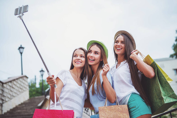 Três belas mulheres jovens caminham na cidade, usando telefone ao ar livre
 - Foto, Imagem