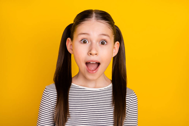 Photo of young attractive school girl amazed shocked surprised fake novelty isolated over yellow color background - Foto, Bild