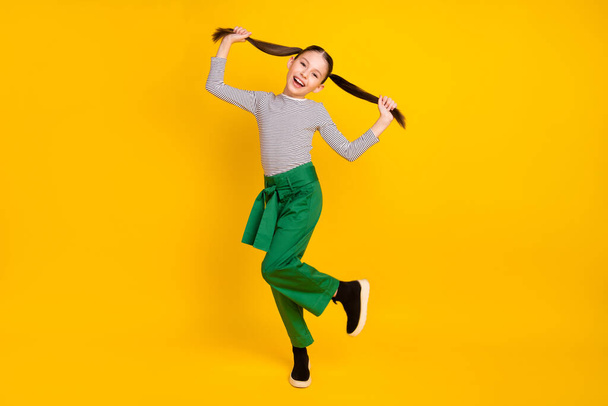 Teljes hosszúságú fotó a fiatal izgatott lány boldog pozitív mosoly jó szórakozást bolondozás elszigetelt sárga szín háttér - Fotó, kép