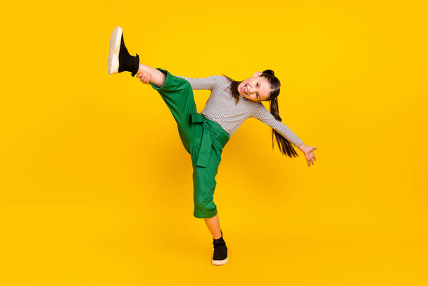 Full length photo of young school girl happy positive smile acrobatics training isolated over yellow color background - Fotó, kép