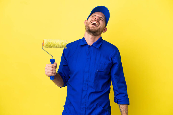 Painter Brazilian man isolated on yellow background laughing - Photo, Image
