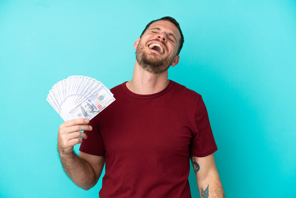 Jeune homme brésilien prenant beaucoup d'argent sur fond isolé rire - Photo, image
