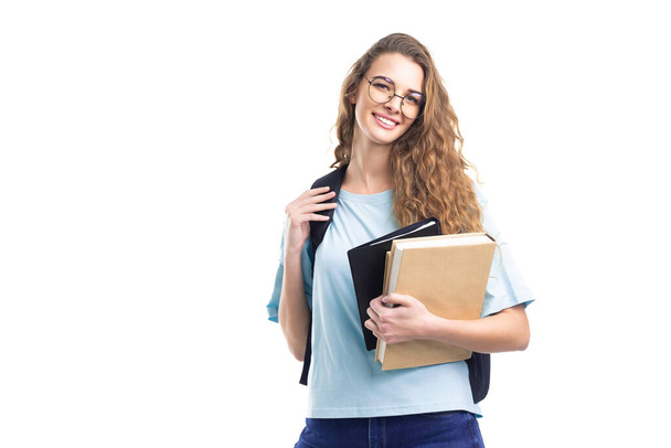 smiling student girl holds books while looking at camera. Over white background. Education. - Foto, Imagem