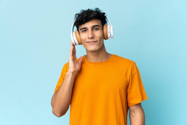 Jonge Argentijnse man geïsoleerd op de achtergrond luisteren muziek - Foto, afbeelding