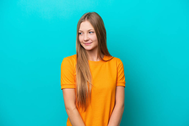 Young Russian woman isolated on blue background having doubts while looking side - Foto, Imagem