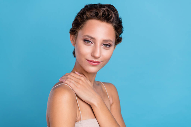 Photo of shiny sweet young woman dressed beige top arm hand neck smiling isolated blue color background - Photo, Image
