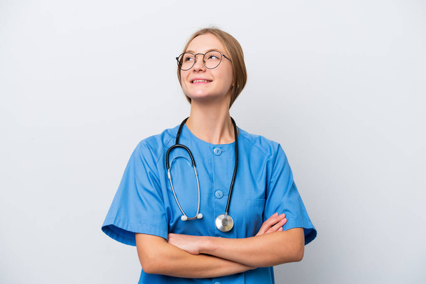 笑顔で見上げながら白い背景に孤立した若い看護師の医師の女性 - 写真・画像