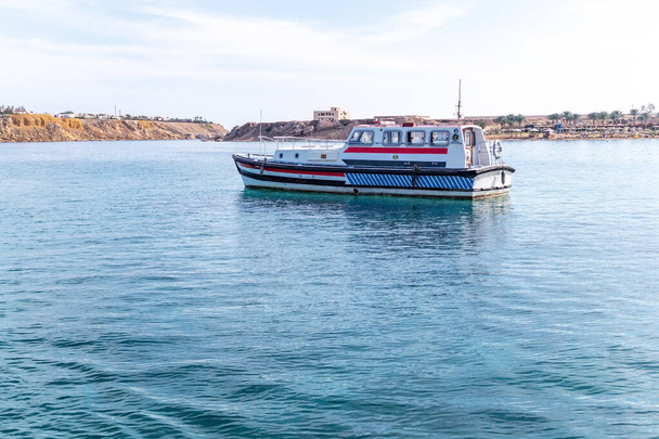 Шарм-эль-Шейх, Египет - 30 ноября 2021 года: Удовольствие туристические и патрульные лодки пришвартованы в гавани Шарм-эль-Шейх в Египте. Яркая лазурная вода Красного моря и туристический пляж - Фото, изображение