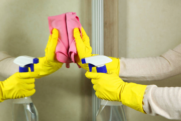 Woman in gloves wipes the mirror with detergents close-up - Zdjęcie, obraz