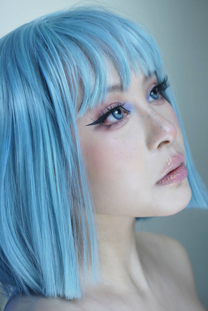 Pretty Asian girl with blue hair represents the LGBT community. She has blue eyes and smooth white skin with a glam look. - Фото, изображение