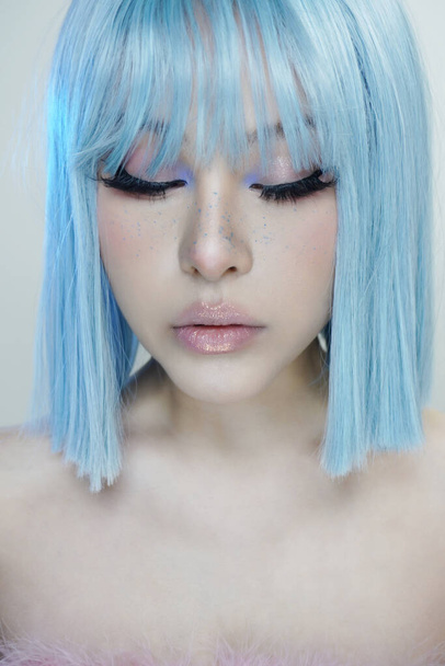 Όμορφη Ασιάτισσα με μπλε μαλλιά αντιπροσωπεύει την ΛΟΑΤ κοινότητα. Έχει μπλε μάτια και απαλό λευκό δέρμα με λαμπερό βλέμμα.. - Φωτογραφία, εικόνα