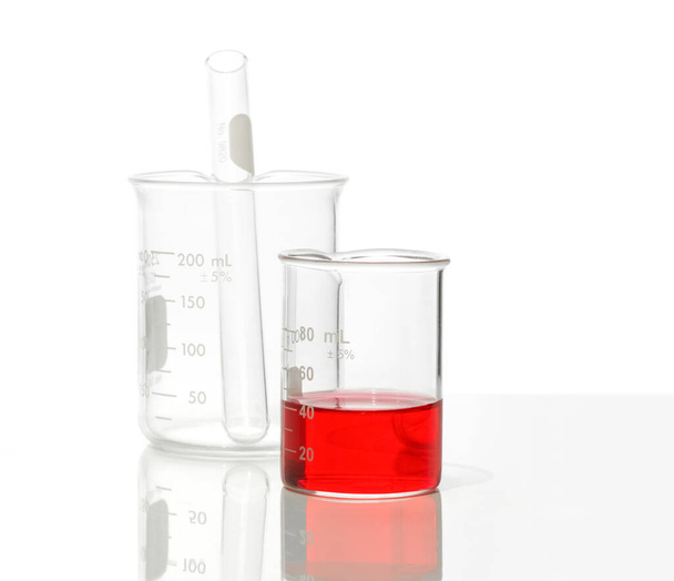 Szekrény kémiai összetevő a fehér laboratóriumi asztalon. Kálium-ferrikanid folyadék főzőpohárban. Oldalnézet - Fotó, kép