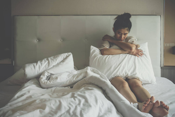 Portret van een depressieve vrouw die alleen op het bed in de slaapkamer zit. Conceptueel van slechte conditie van gebroken hart, verdriet, eenzaamheid vrouw. - Foto, afbeelding
