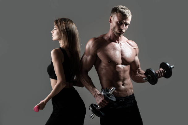 Muscular sexy couple body. Sports people are working out with dumbbells. Fit couple doing exercise with dumbbells in dark studio. - Фото, зображення