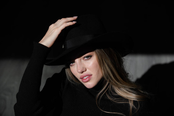 Girl in fashion hat. Sexy alluring woman, sensual young model looking seduce on black studio. Fashion portrait of elegant woman in shadow, glamor light. - Fotó, kép